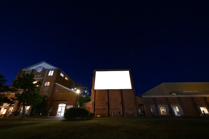 広場の中の建物にスクリーンを設置「空の映画館」
