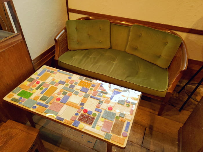 ソファ席とガラスや手作りタイルが可愛らしく配置されたテーブル